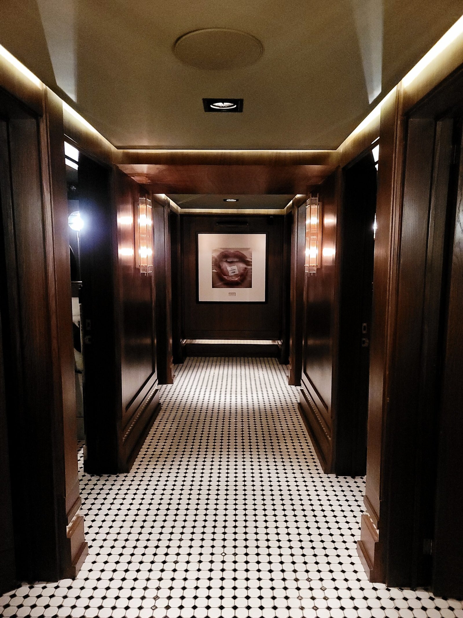 un pasillo largo con un suelo de azulejos y una imagen en la pared