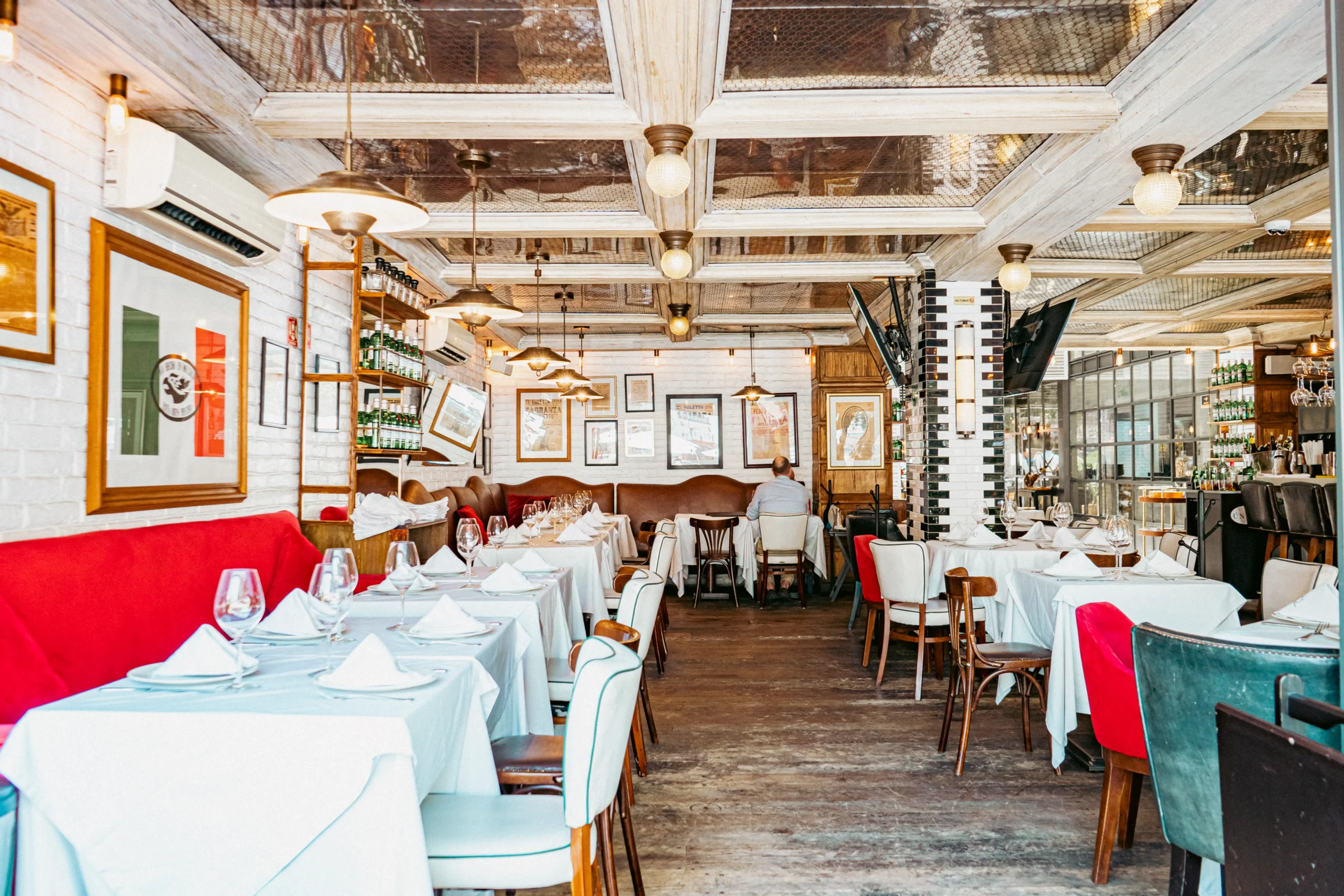 mesas y sillas en un restaurante con un sofá rojo y manteles blancos