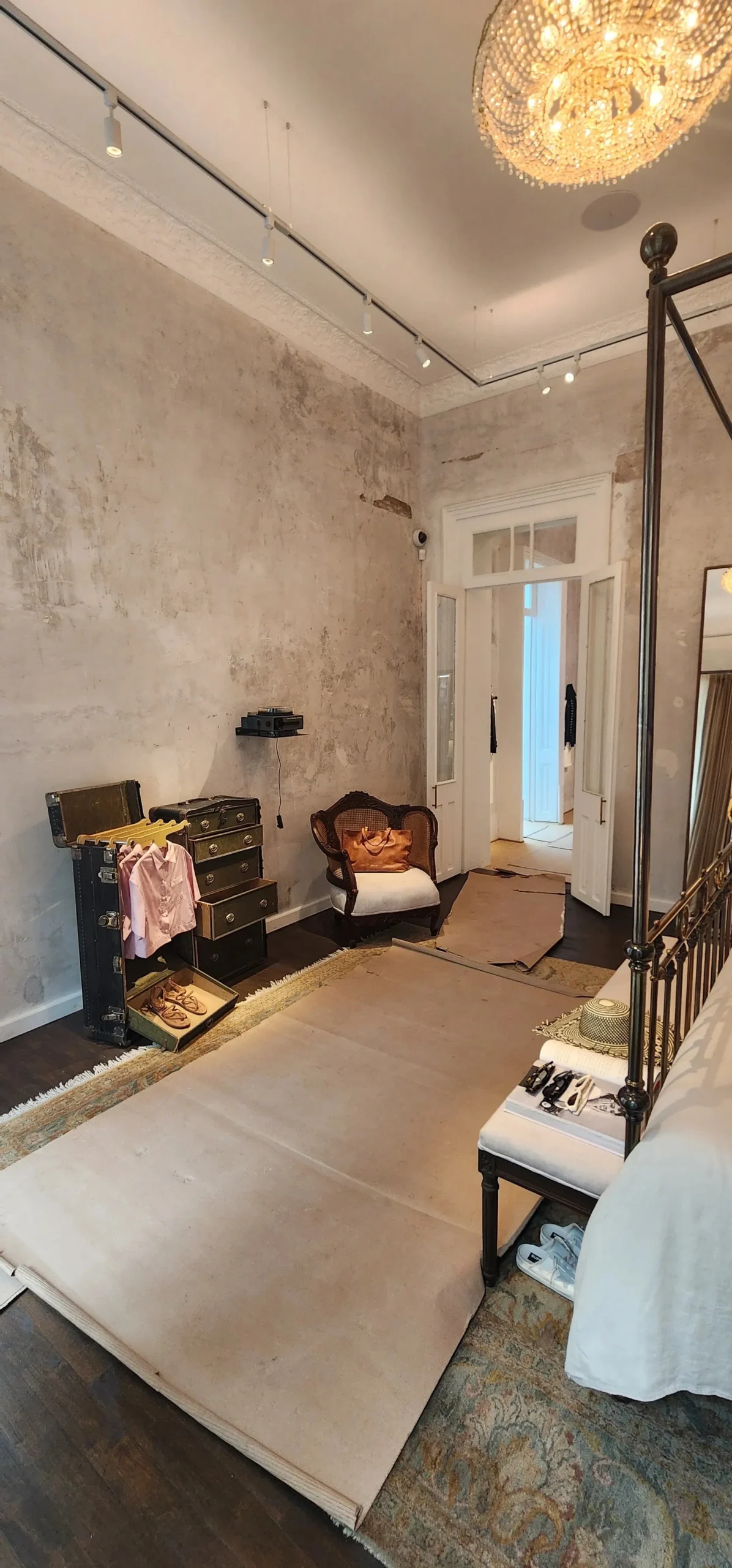 hay un dormitorio con una cama una silla y una lámpara de araña