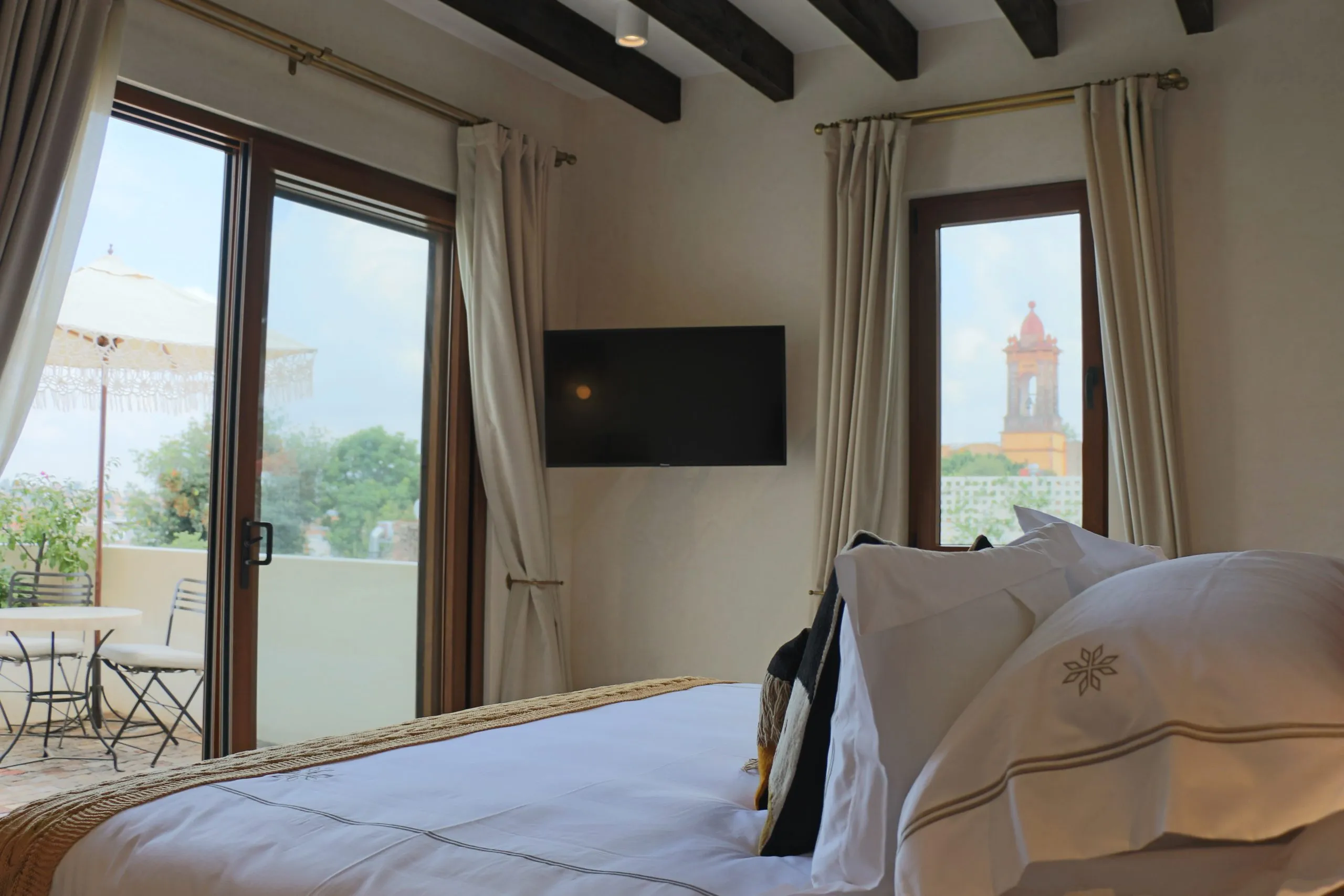 hay una cama con almohadas y un televisor en la pared