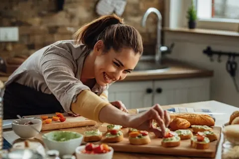 una mujer preparando comida en una tabla de cortar de madera