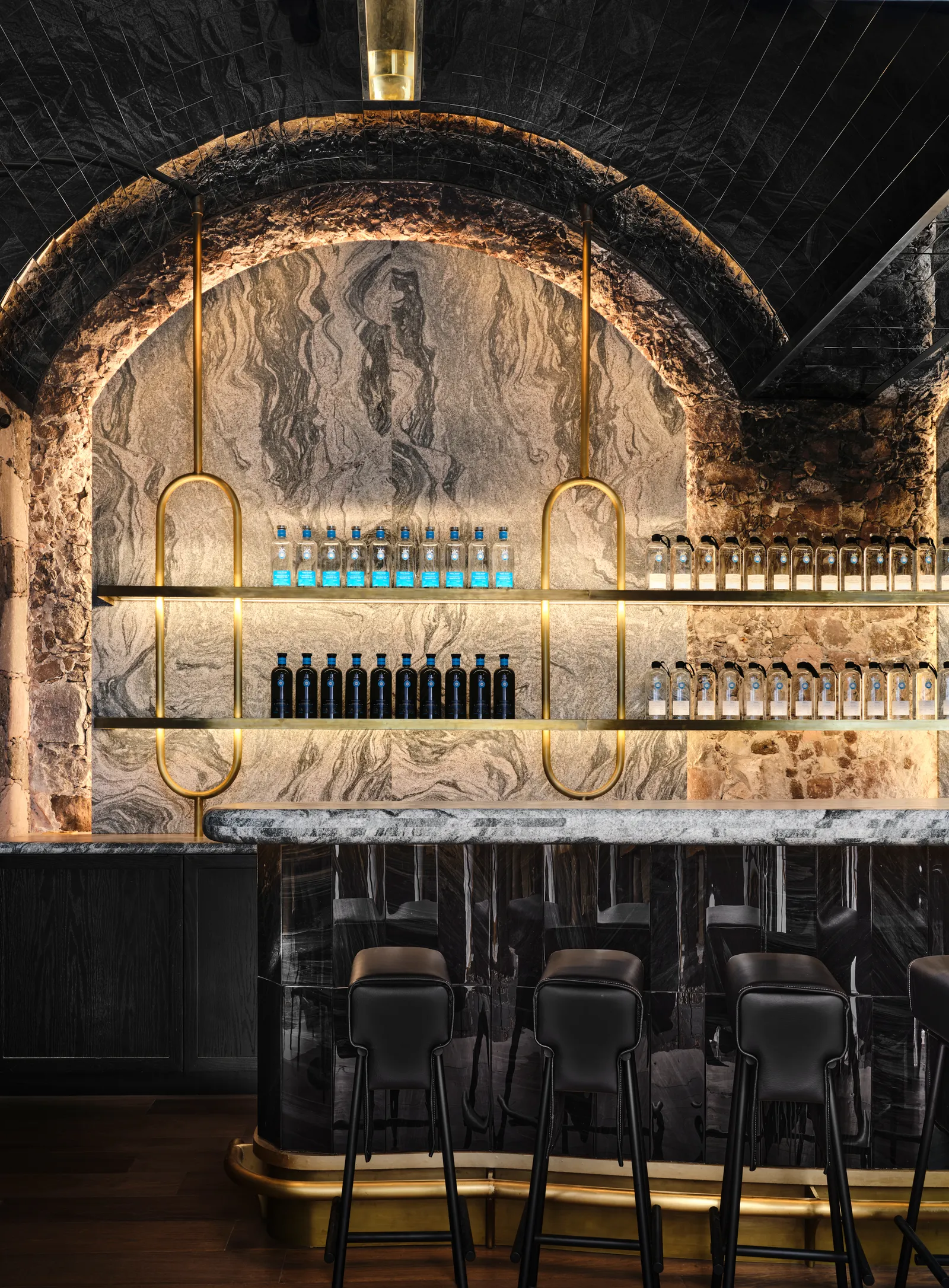 un bar con una pared de mármol y un taburete de oro