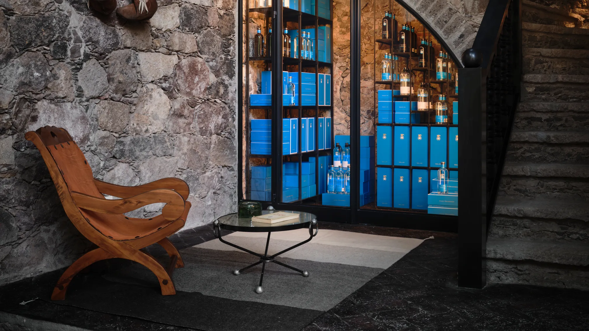 una silla y una mesa delante de la pared de piedra