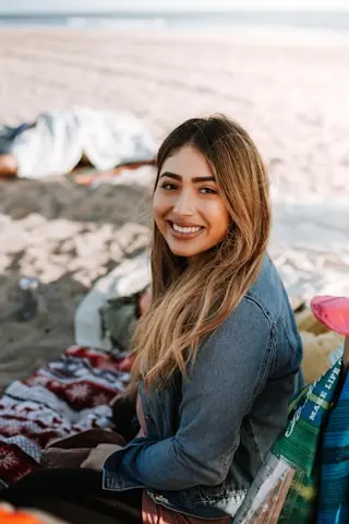 una mujer sentada en la playa con su manta de picnic