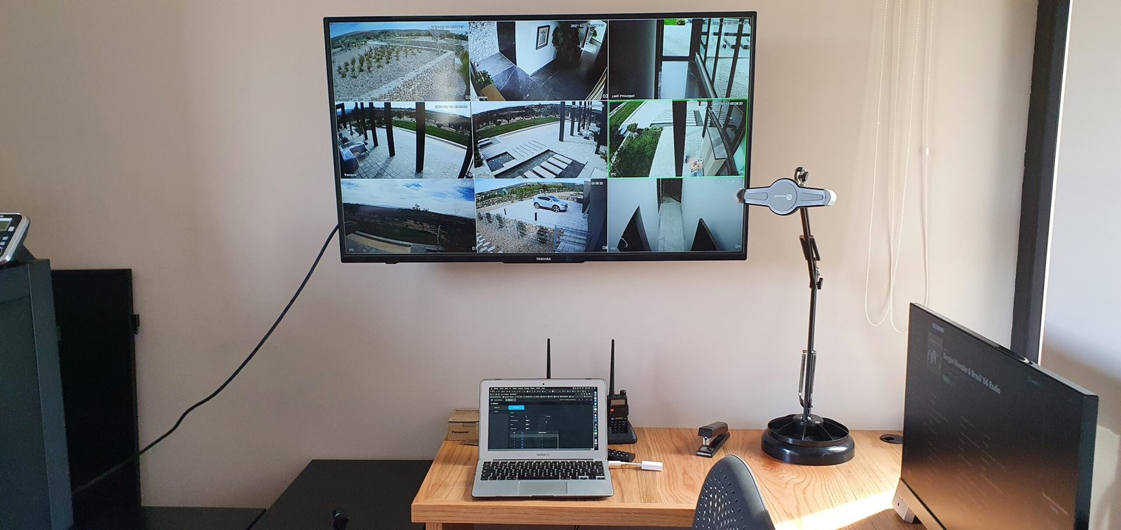 hay un ordenador portátil y un monitor en un escritorio frente a un televisor