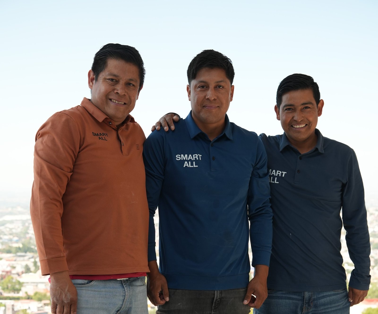 tres hombres de pie uno al lado del otro frente a una ciudad